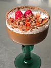 Chocolate mousse in a glass, topped with cream, raspberries and chocolate shavings.