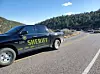 Sheriff pickup truck blocks a curved mountain highway with other vehicles ahead.